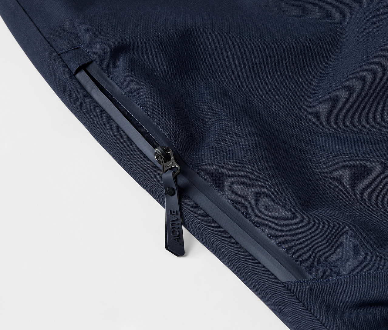 Detailaufnahme einer dunkelblauen Jacke mit Reissverschluss und Logo.