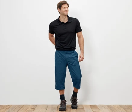 Mann steht und trägt blaue 3/4-Cargo-Bermudas.