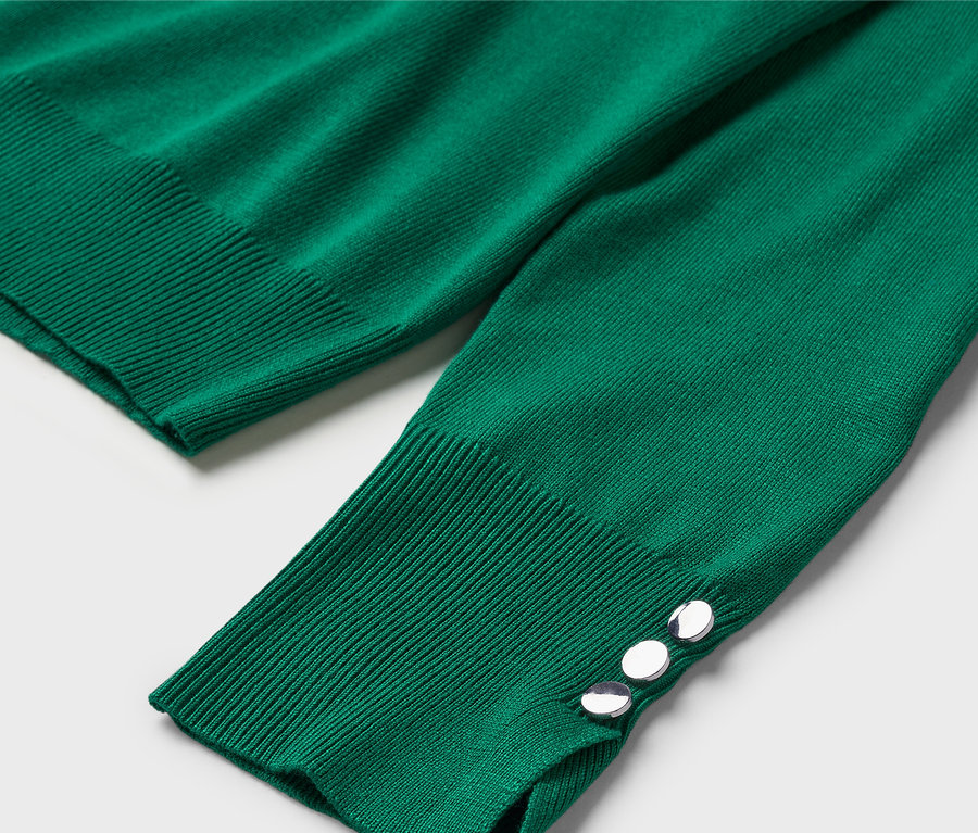 Detailaufnahme eines grünen Pullovers mit langen Ärmeln und dekorativen Knöpfen am Ärmelbund.