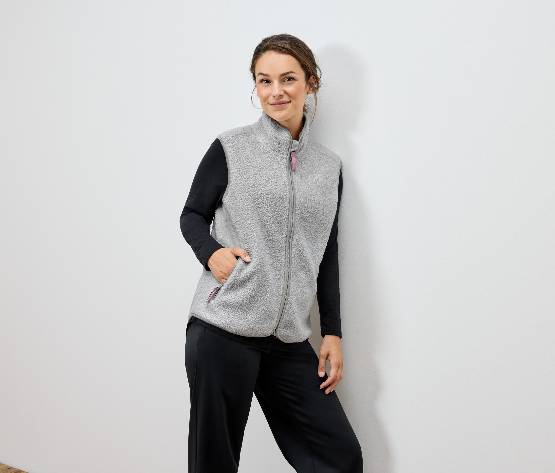 Frau trägt eine graue Fleeceweste und eine schwarze Hose.