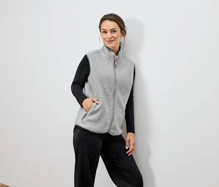 Frau trägt eine graue Fleeceweste und eine schwarze Hose.