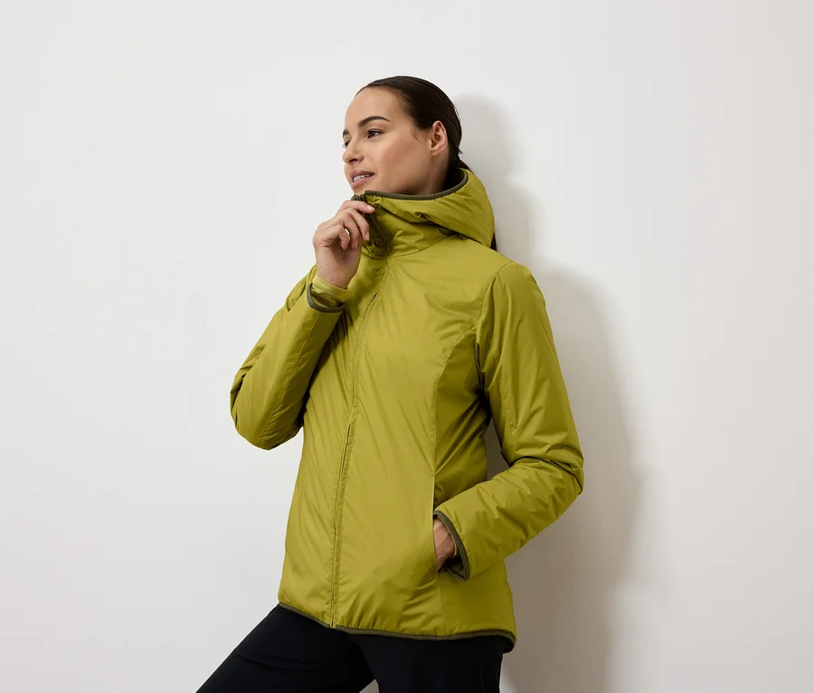Frau schließt eine gelbgrüne Jacke mit Kapuze.