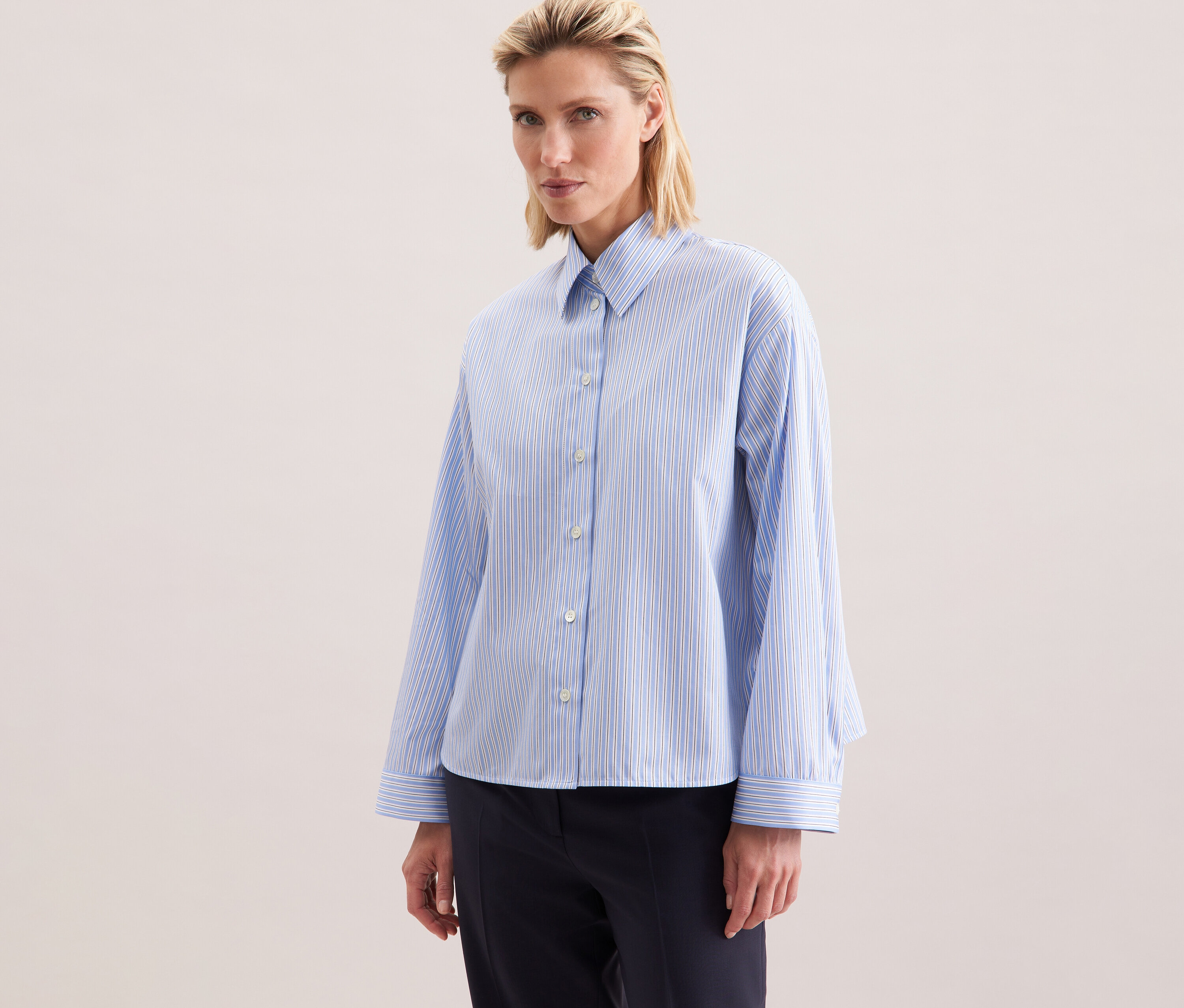 Frau trägt eine Seidensticker Oversize-Hemdbluse mit blauen Streifen.