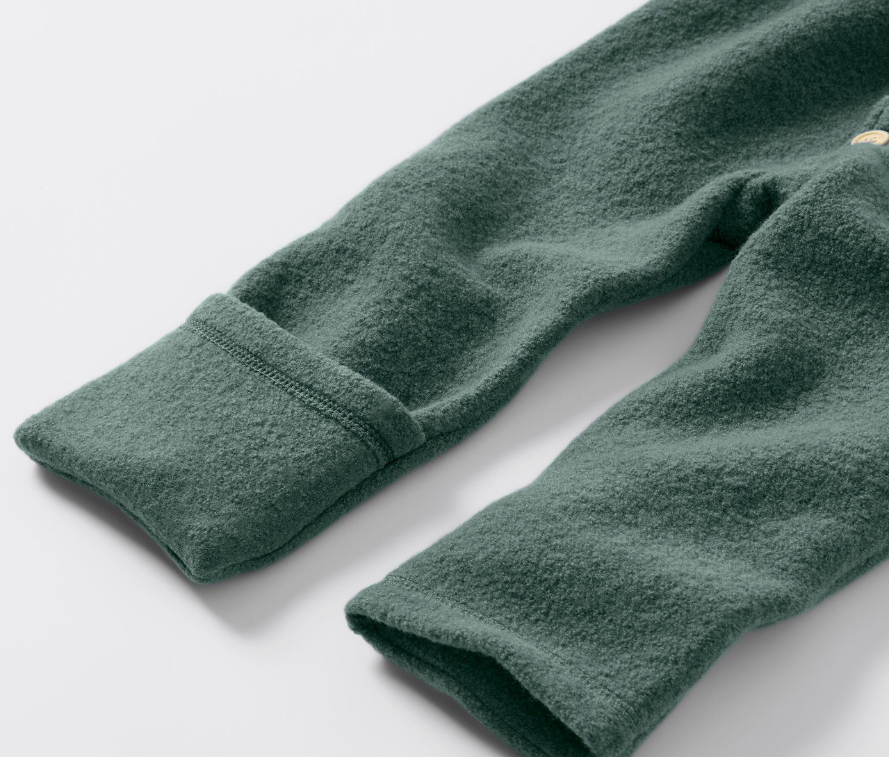 Detailaufnahme eines grünen Baby-Walkoveralls mit Merinowolle.