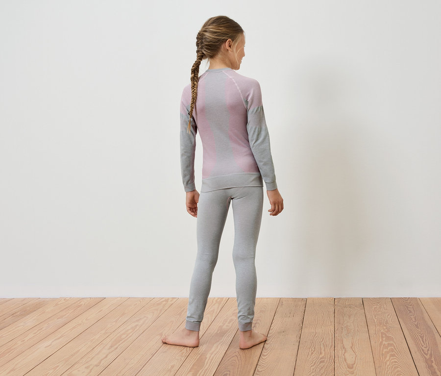 Mädchen mit Zopf steht mit dem Rücken zur Kamera und trägt graue Thermounterwäsche.