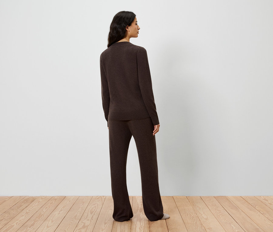 Rückansicht einer Frau in braunem Strickpullover und Hose.