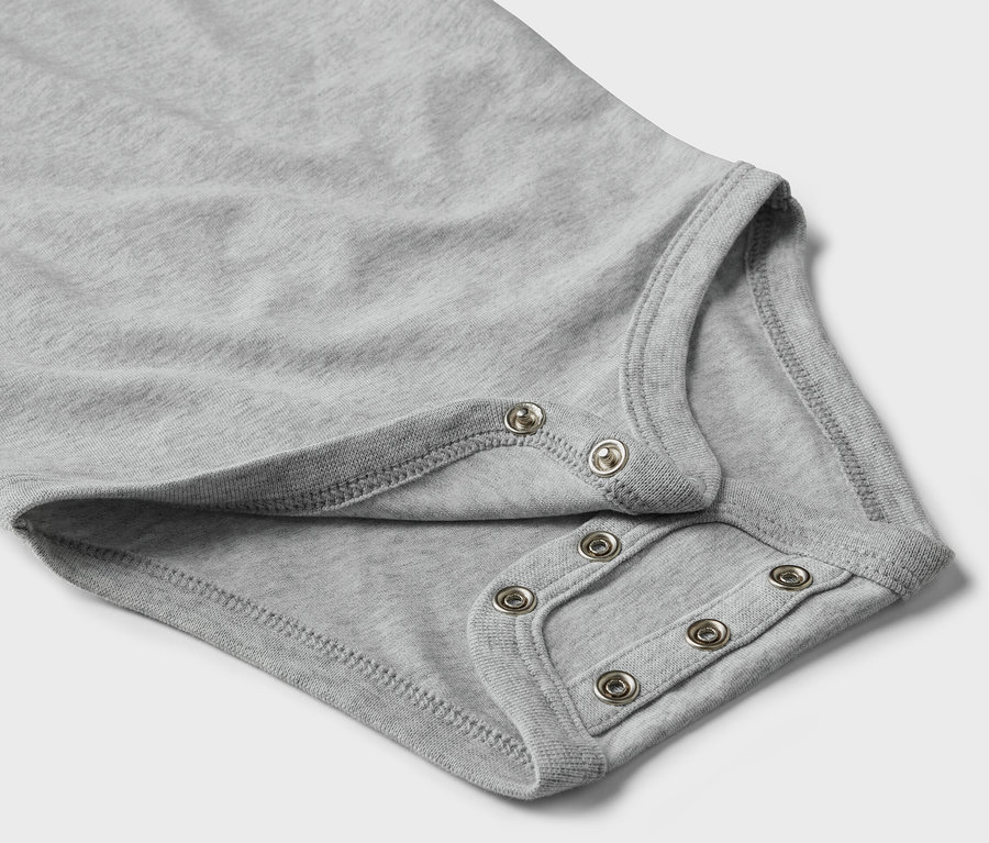 Detailansicht eines grauen Baby-Bodys mit Mitwachsfunktion und Druckknöpfen.