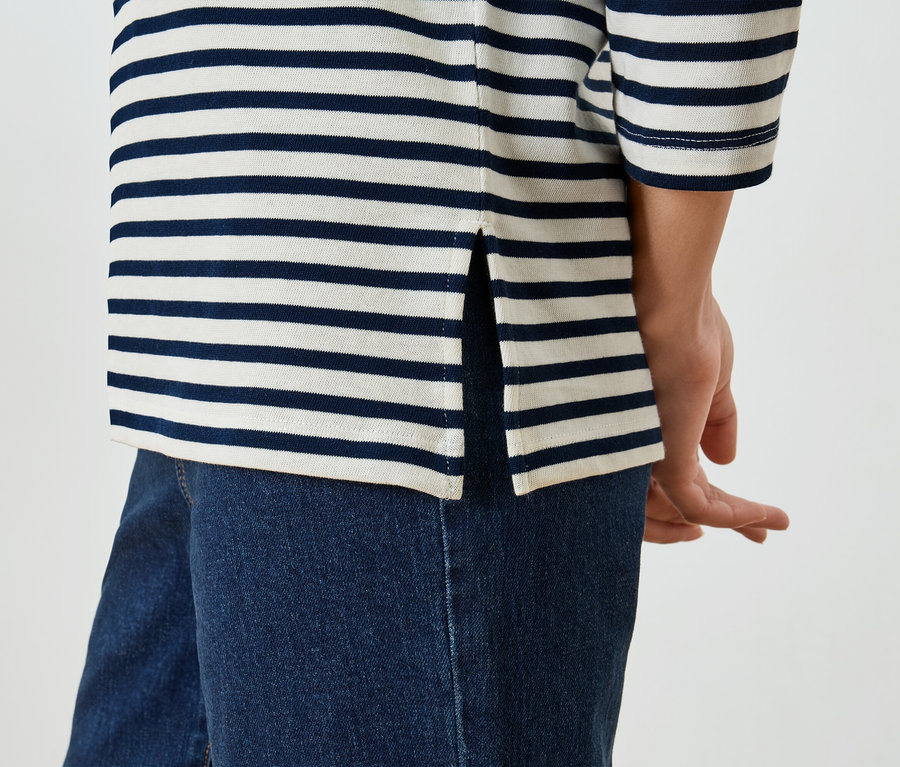 Nahaufnahme einer Person, die ein gestreiftes Oberteil und Jeans trägt.