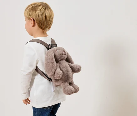 Kind trägt einen grauen Hasenrucksack.