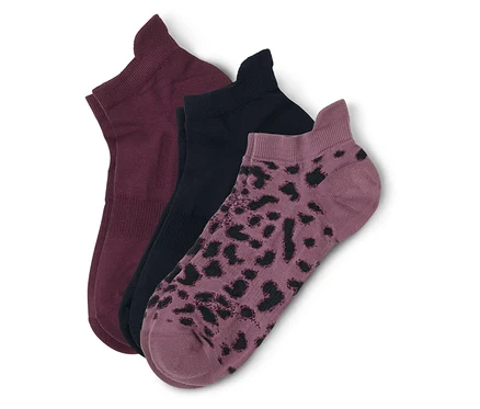 Drei kurze Socken liegen übereinander: eine bordeauxrot, eine schwarz und eine mauvefarben mit schwarzen Flecken.