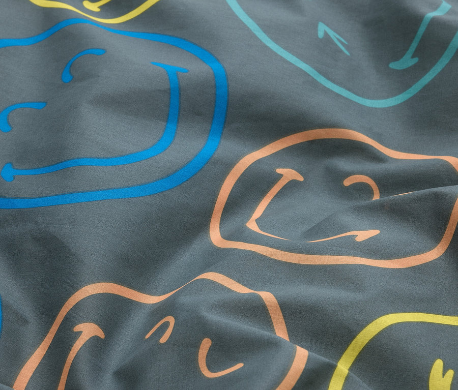 Dunkelgrauer, zerknitterter Stoff mit abstrakten Umrissen von Smileys in Blau, Hellblau, Gelb und Orange.