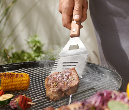 Mann grillt Steak mit BBQ-Multitool.