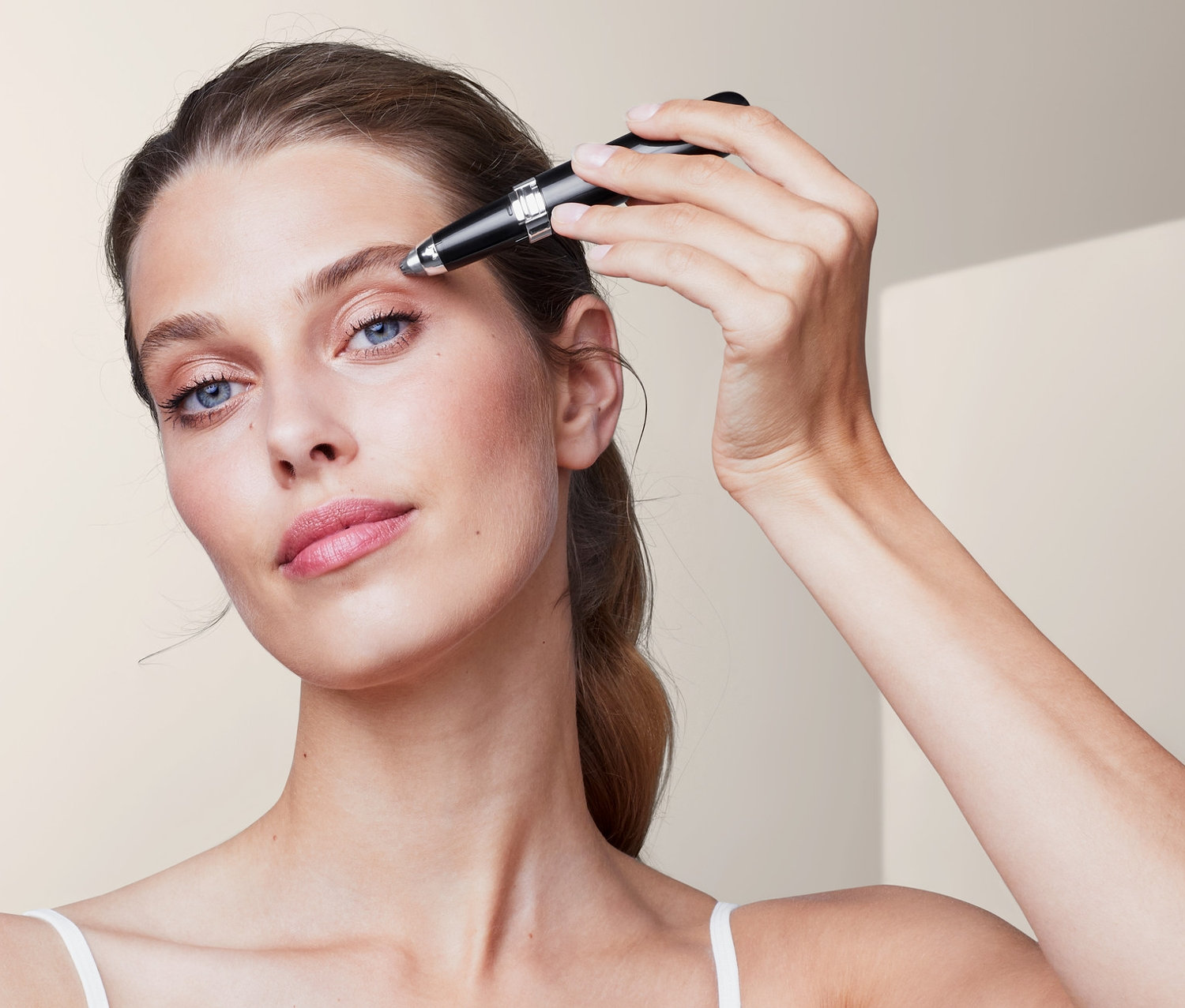 Frau verwendet elektrischen Augenbrauenstyler.
