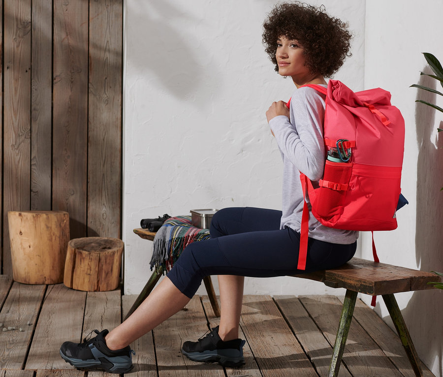 Frau sitzt mit rotem Outdoor-Rucksack.