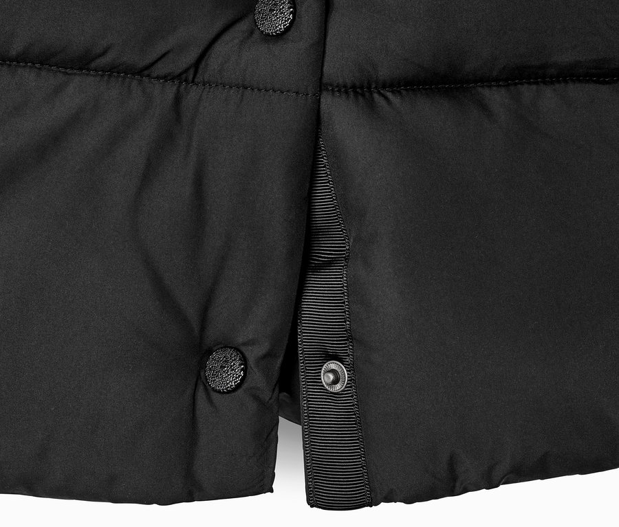 Detailansicht eines schwarzen Steppmantels mit Kapuze und Knöpfen.