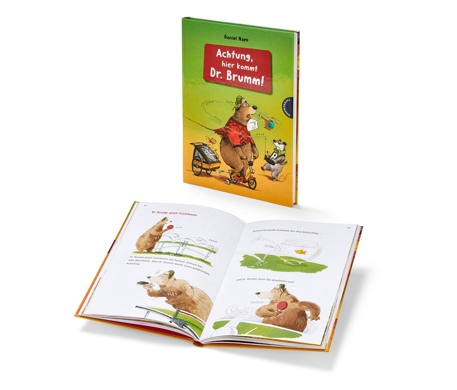 Geöffnetes Buch mit Illustrationen neben Buch "Achtung, hier kommt Dr. Brumm!"
