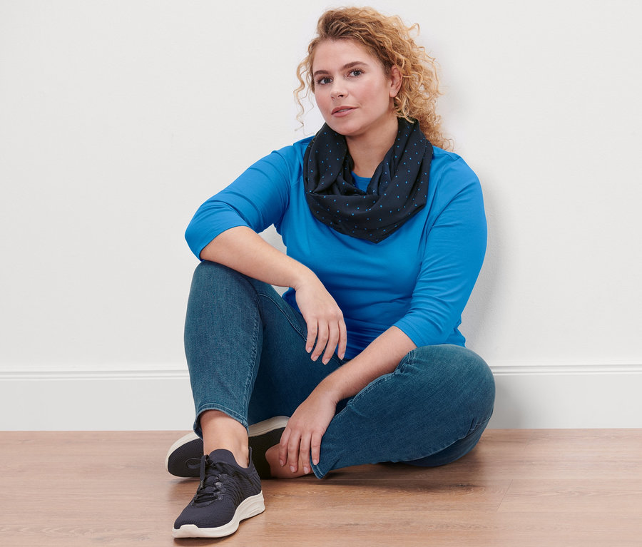 Eine Frau sitzt auf dem Boden und trägt ein azurblaues Shirt mit 3/4-Arm, Treggings »Fit Nelly« und einen gepunkteten Loop-Schal.