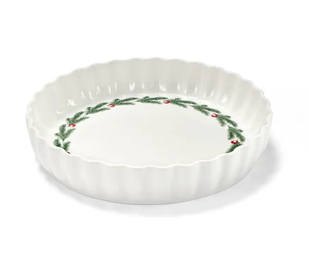 Eine weiße Tortenform mit Weihnachtsmotiv aus Tannenzweigen und roten Beeren.