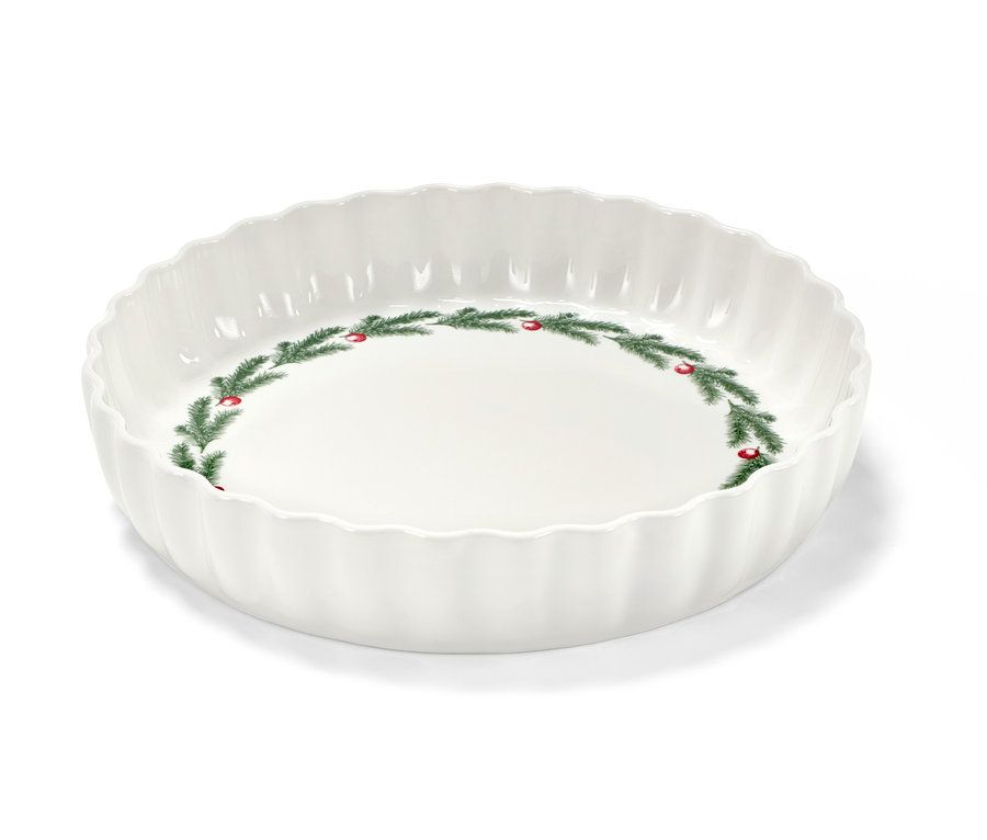 Eine weiße Tortenform mit Weihnachtsmotiv aus Tannenzweigen und roten Beeren.