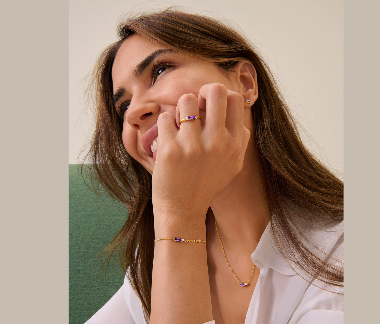 Frau lächelt und berührt ihr Gesicht mit der Hand, sie trägt einen 925 Silber Ring, Ohrstecker, Armband und eine Kette.