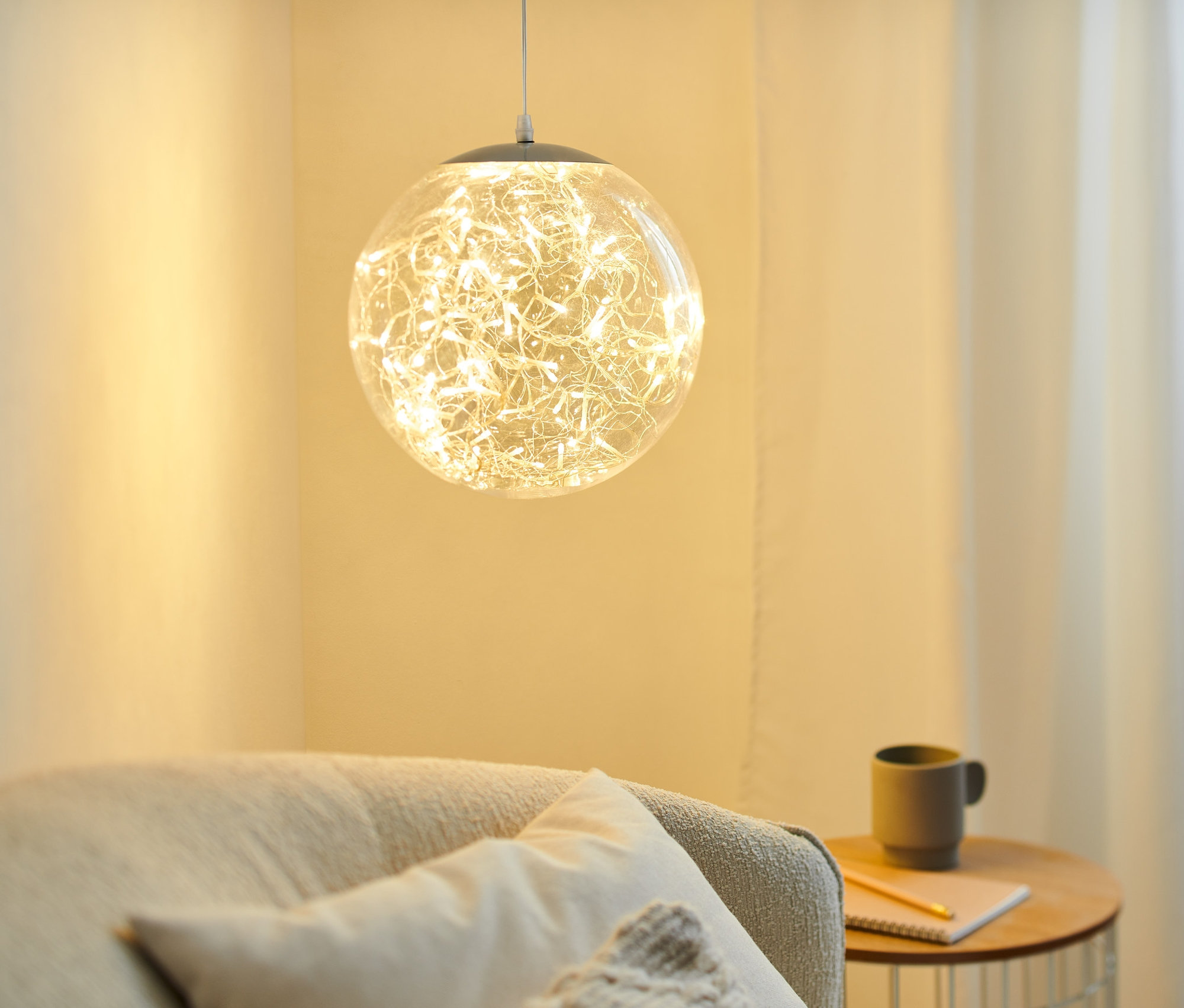 Eine ca. 30 cm große LED-Kugel hängt und beleuchtet ein Wohnzimmer.