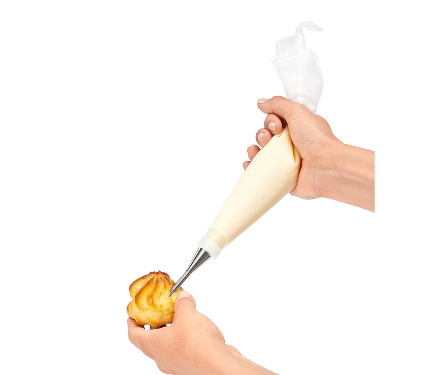 Eine Hand füllt einen Windbeutel mit Creme mit einem Spritztüllen-Set.