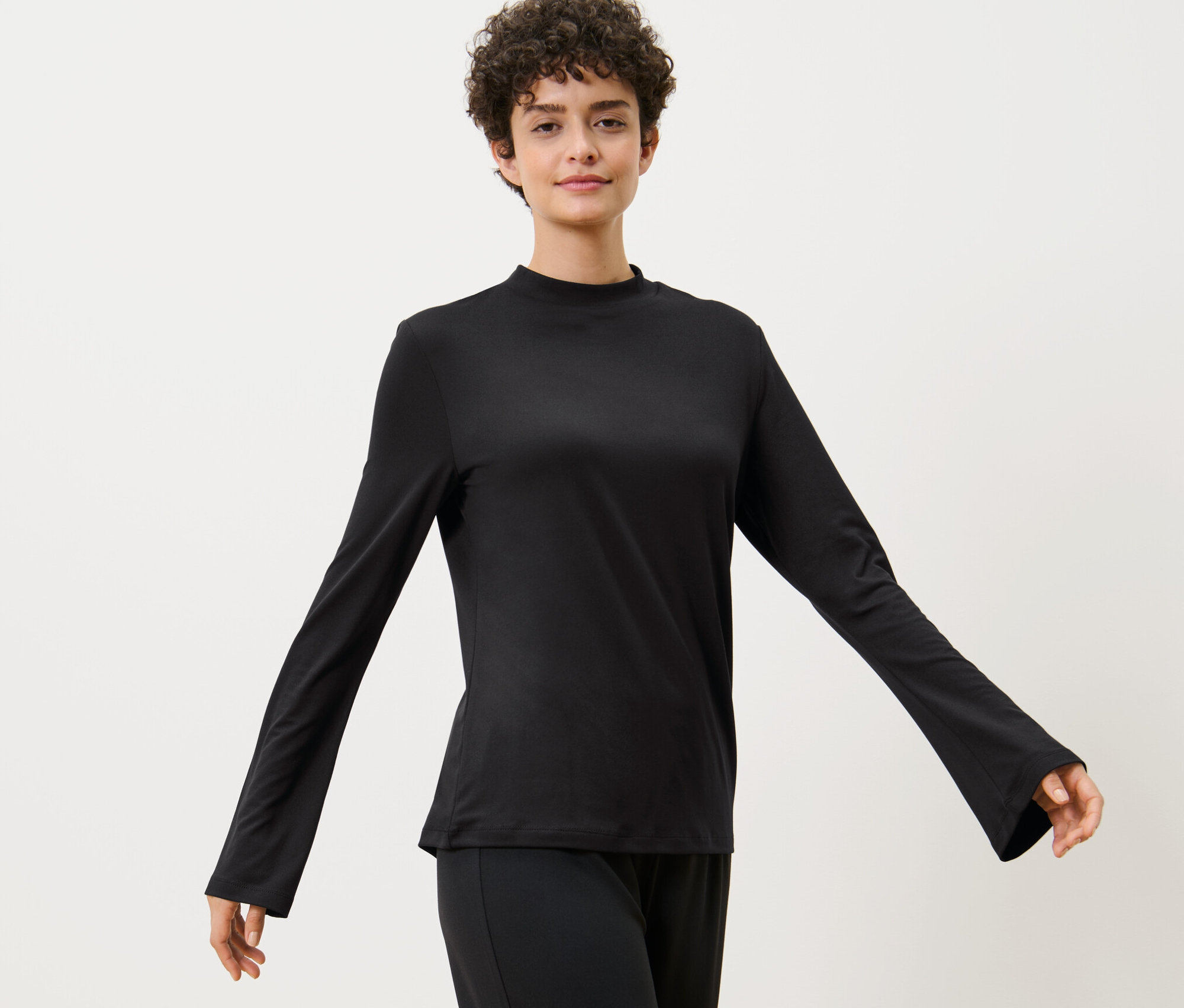 Frau posiert in einem Langarm-Sportshirt.