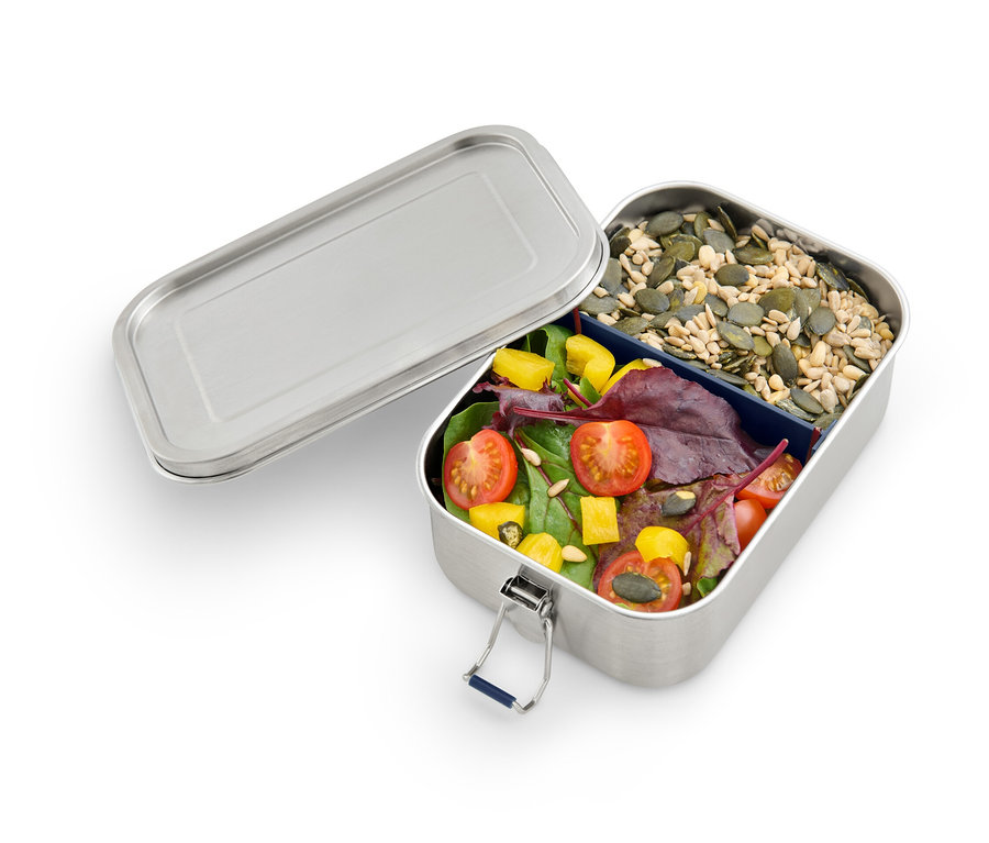 Geöffnete To-go-Lunchbox mit Tomaten, Salat und Kürbiskernen.