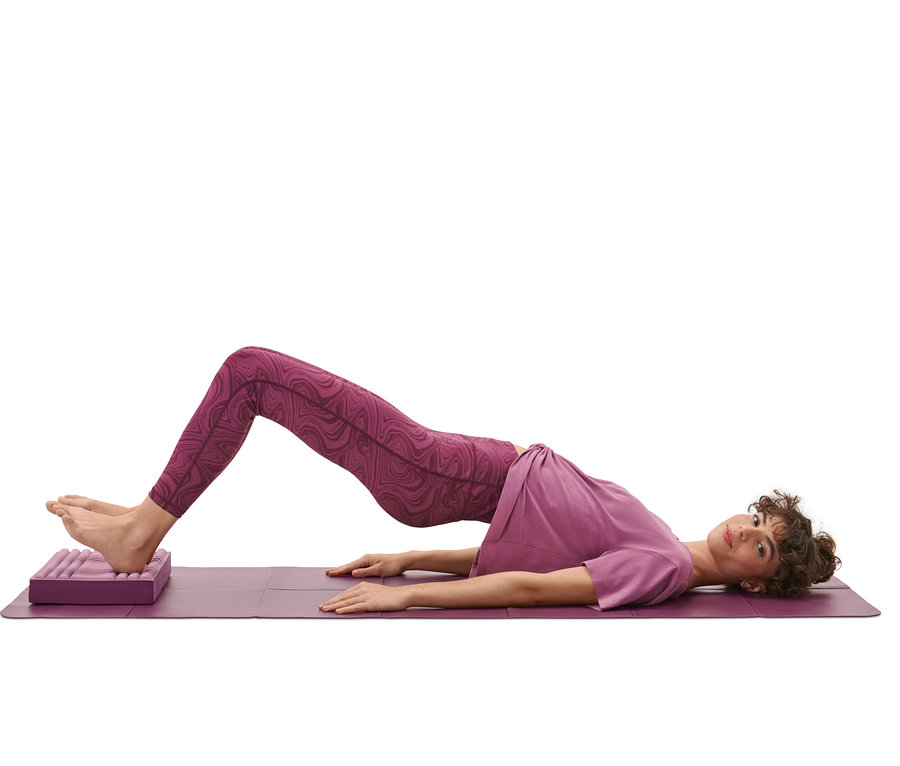 Frau macht eine Brücke auf einem Balance- und Massage-Pad.