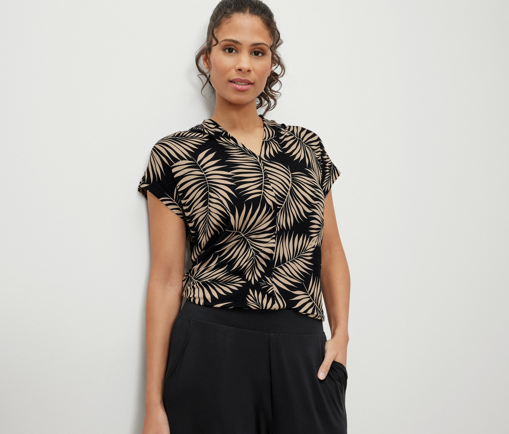 Frau trägt ein bedrucktes Blusenshirt mit V-Ausschnitt.