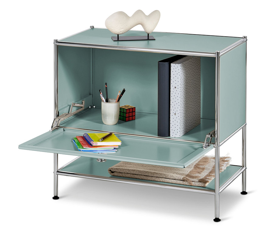 Ein blaugrüner Schrank mit geöffneter Tür und Regalen, auf denen Bücher, Stifte, ein Rubik's Würfel, Notizblöcke und eine Decke liegen.