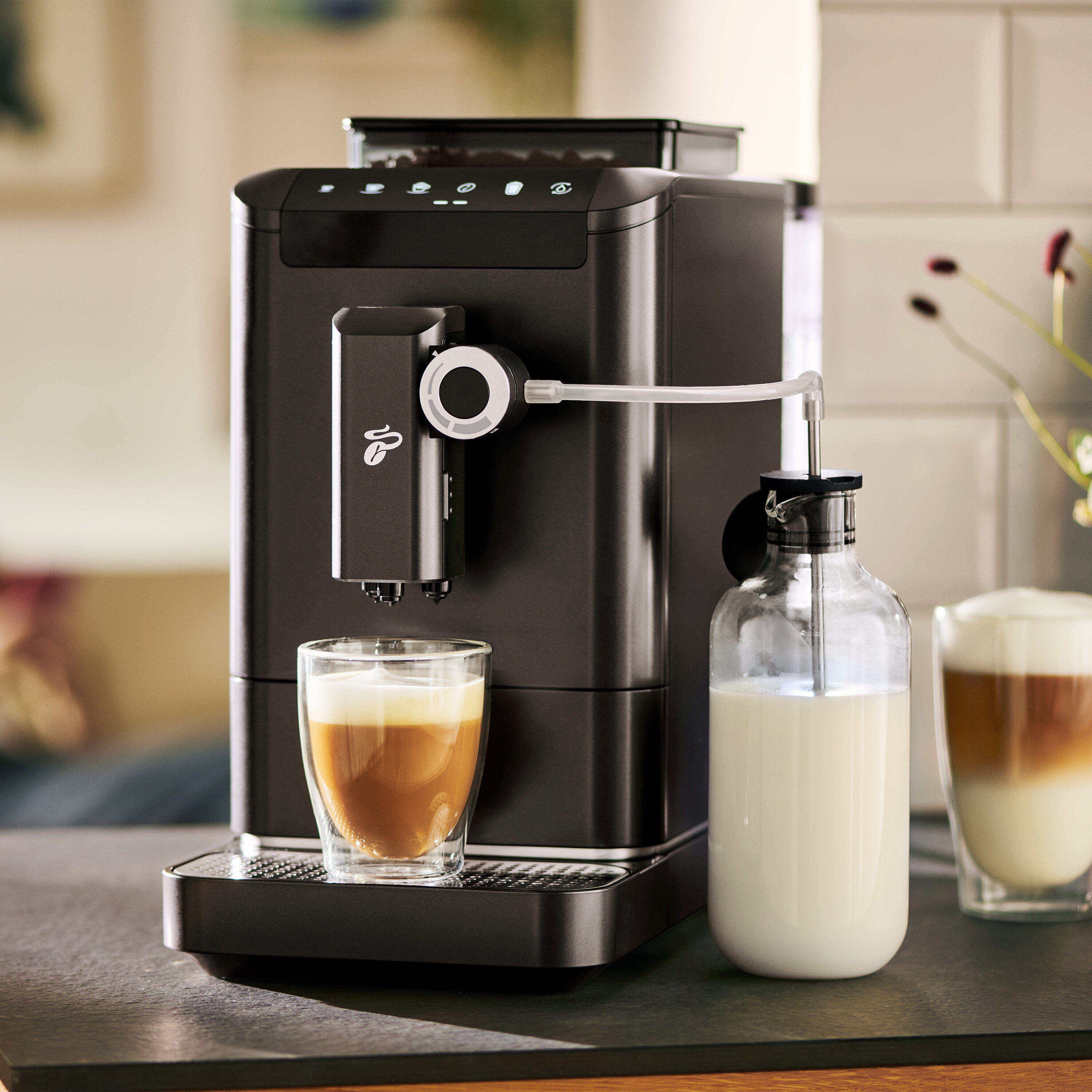 Ein Kaffeevollautomat bereitet Kaffee in einem Glas neben einer Milchflasche zu.