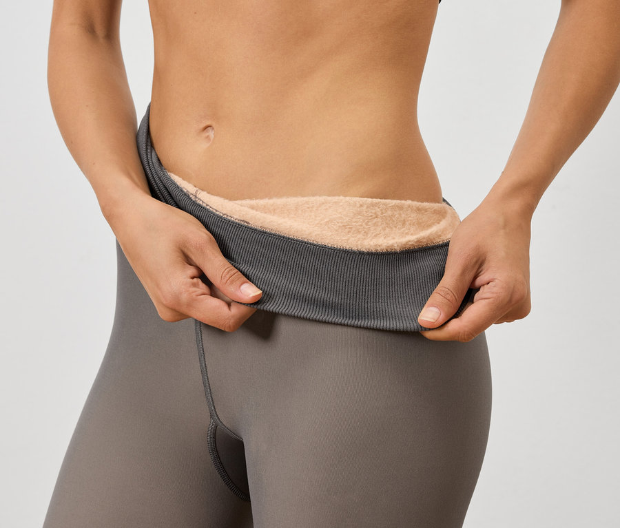 Frau hält graue Leggings mit warmem Futter hoch.