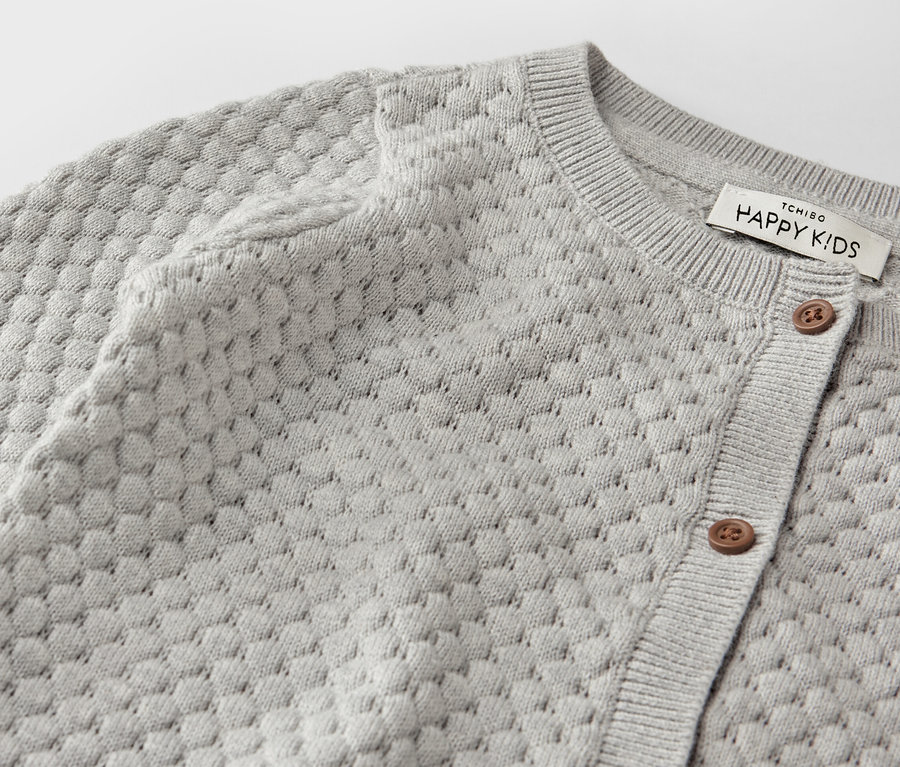 Detailaufnahme einer grauen Baby-Strickjacke.