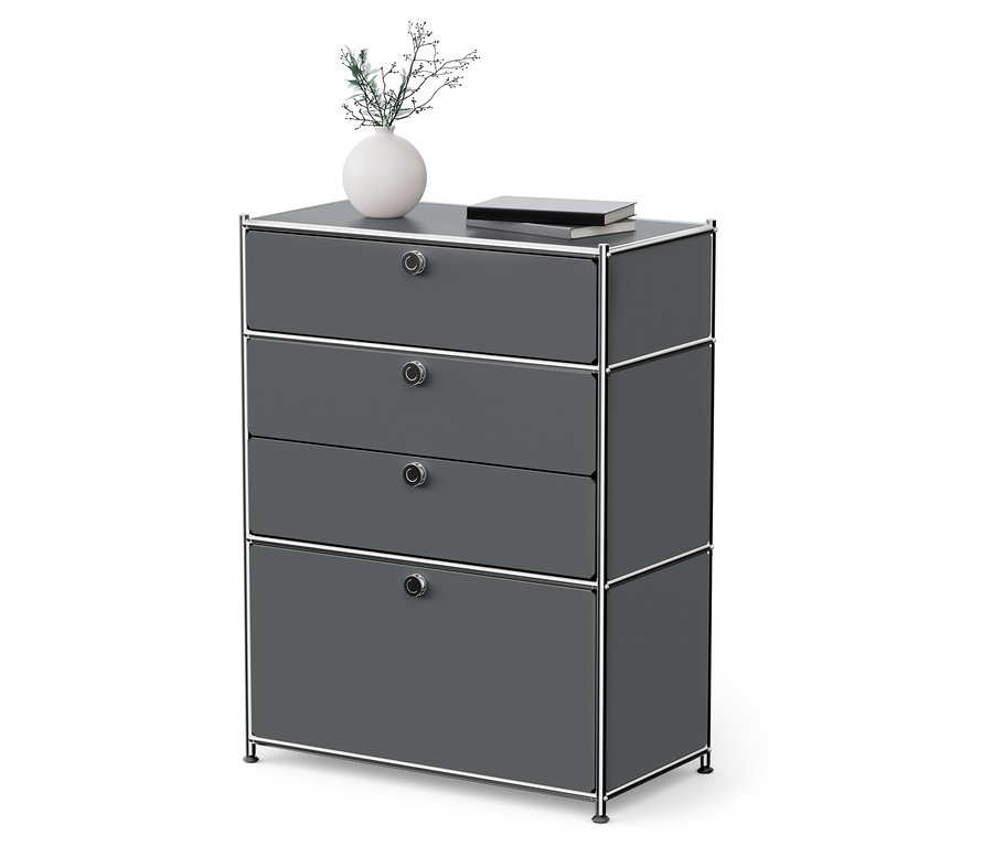 Graue Kommode mit vier Schubladen und Chromrahmen. Auf der Kommode stehen eine Vase mit Blumen und ein Buch.