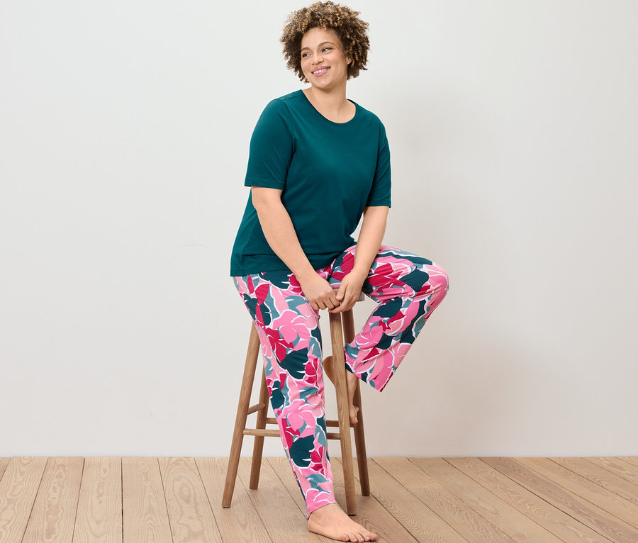 Frau sitzt auf einem Hocker und trägt ein Pyjama-Set.