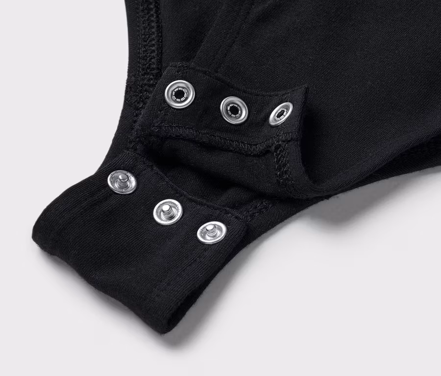 Detailaufnahme eines schwarzen Bodys mit Druckknöpfen im Schritt.