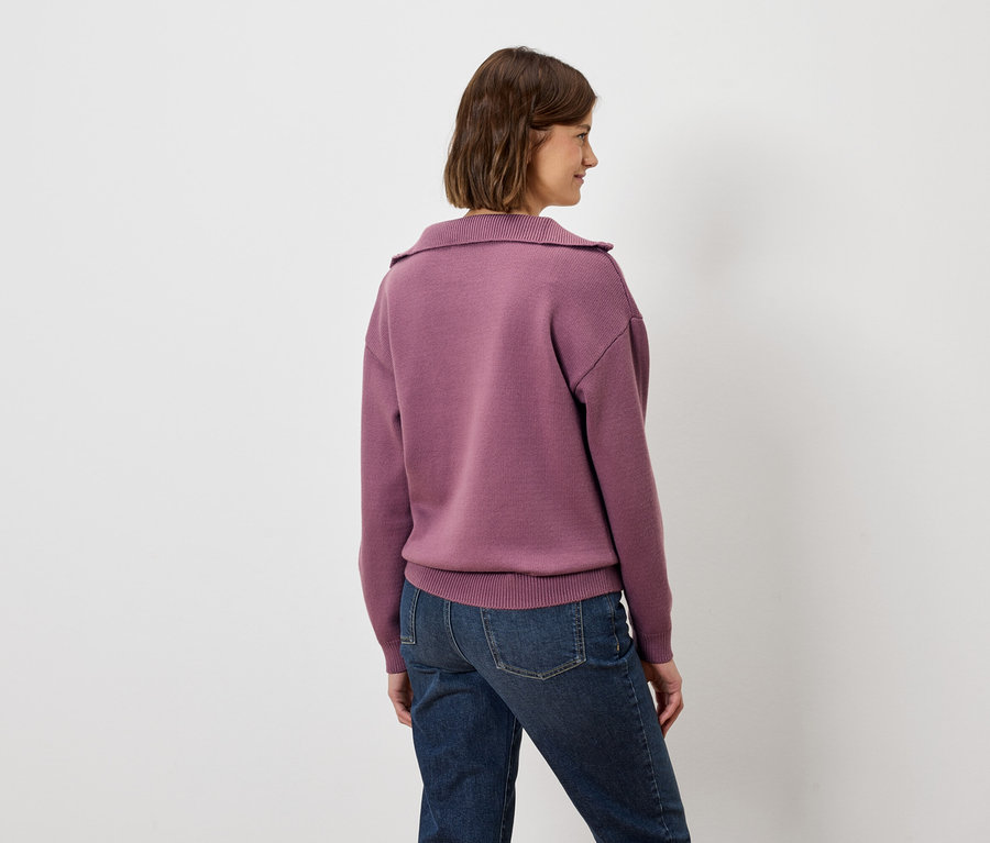 Frau mit dem Rücken zur Kamera trägt ein violettes Sweatshirt und Jeans.