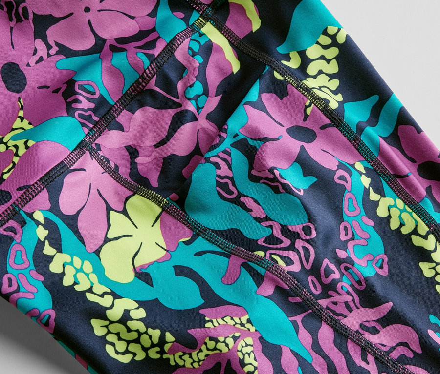 Nahaufnahme einer 3/4-Sporttight mit Alloverprint aus Blumen und Blättern in Pink, Türkis und Gelb.