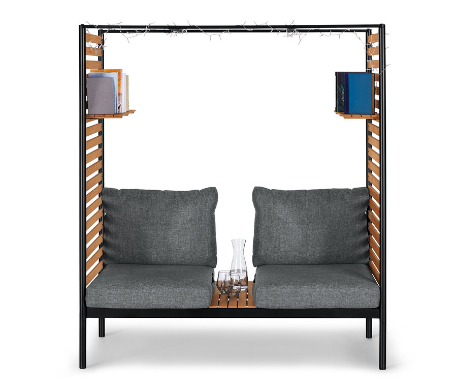 ScanCom Outdoor-Lounge mit Fußhocker, anthrazitfarbenen Kissen, Gläser und Karaffe auf Holztisch.