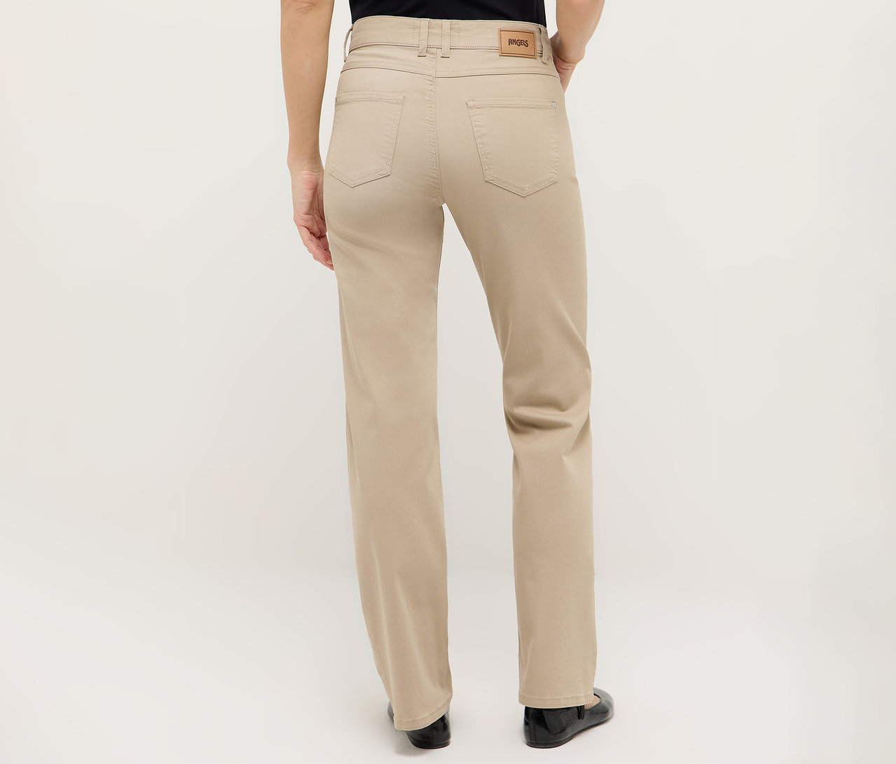 Rückansicht einer Frau, die eine beigefarbene Hose und schwarze Schuhe trägt.