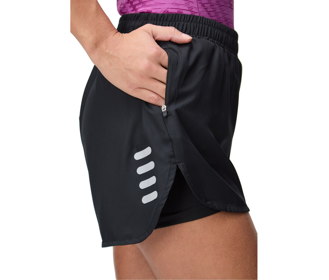 Frau greift in die Reißverschlusstasche einer schwarzen Shorts mit reflektierenden Streifen.