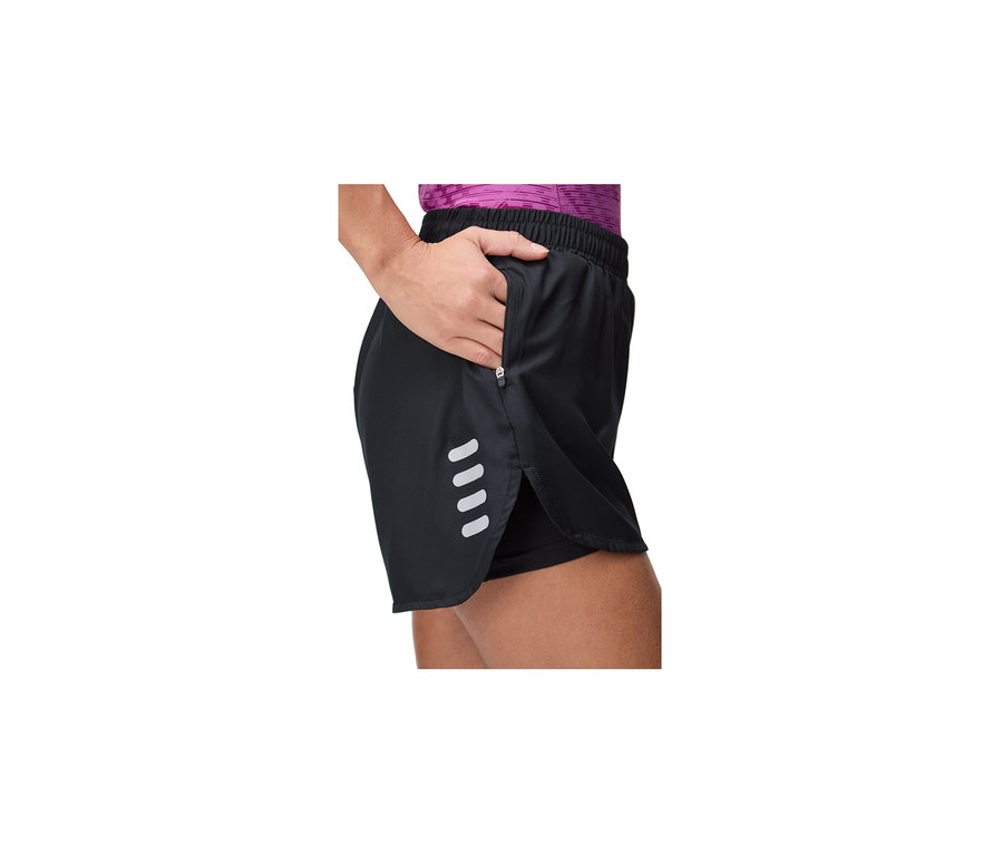 Frau trägt schwarze FILA Damen-Funktionsshorts mit Reißverschlusstasche, reflektierenden Streifen und sichtbarer Innenschicht, ihre Hand steckt in der Tasche.