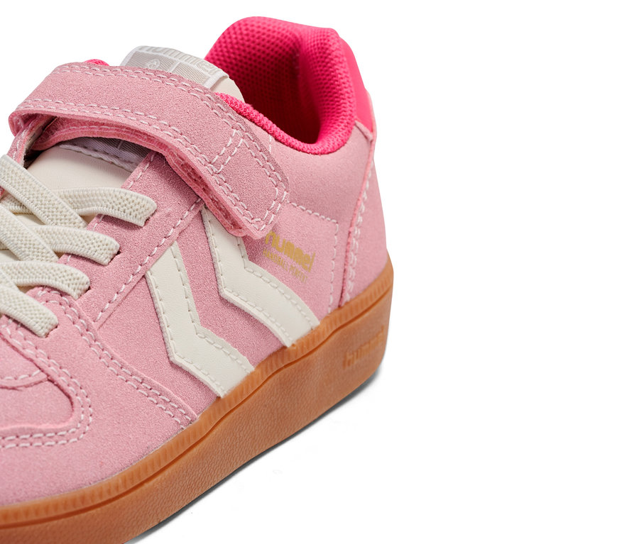 Nahaufnahme eines einzelnen, hellrosa farbenen Sneakers mit Klettverschluss und weißen Schnürsenkeln.
