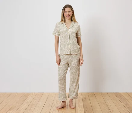 Frau in hell gemustertem Pyjama-Set aus Oberteil mit Knopfleiste und Hose.