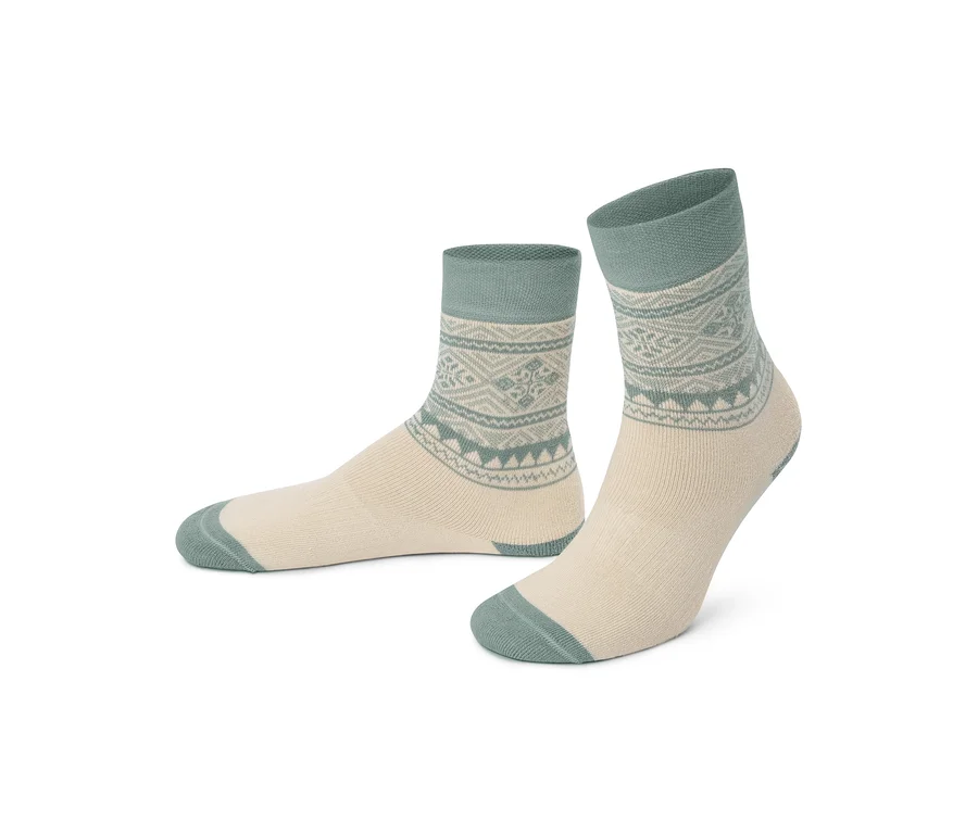 Ein Paar cremefarbene Socken mit türkisen Bündchen, Fersen und Zehen, verziert mit einem türkisen geometrischen Muster um die Knöchel.
