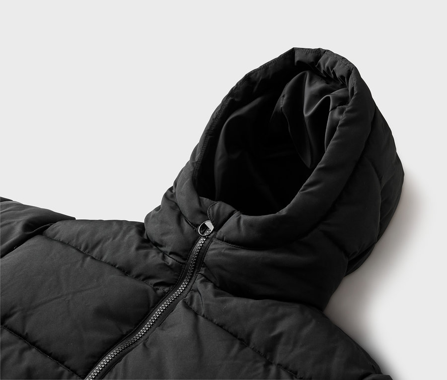 Nahaufnahme einer schwarzen Steppjacke mit Kapuze und Reißverschluss, von oben gesehen.