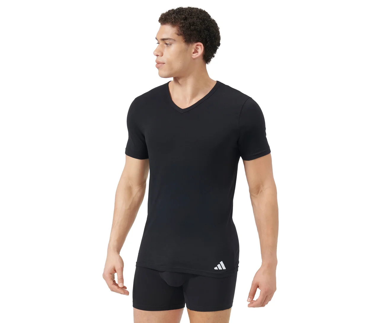 Mann trägt schwarzes V-Ausschnitt T-Shirt und schwarze Boxershorts. Das T-Shirt hat ein weißes Logo unten links. Der Mann blickt nach rechts.