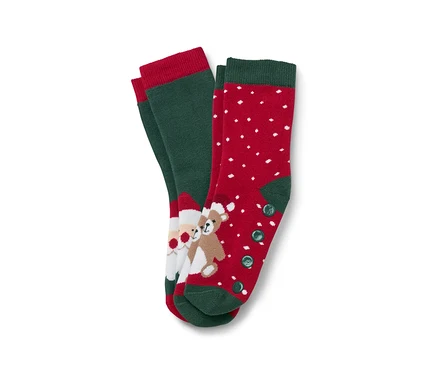 Zwei Paar Weihnachtssocken. Ein Paar ist grün mit rotem Rand und einem Bild von Santa Claus und einem Teddybär. Das andere Paar ist rot mit weißen Punkten und grünem Rand und Knöpfen.