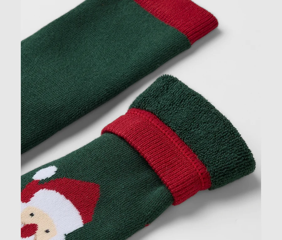 Detailaufnahme einer grünen Socke mit rotem Rand und Weihnachtsmann-Motiv.